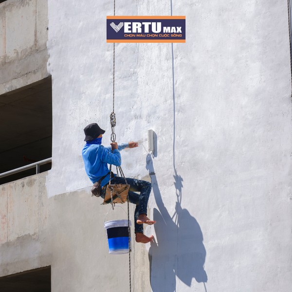 Thợ thi công mặc đồ bảo hộ đang làm việc trên cao, xử lý bề mặt tường bên ngoài công trình.